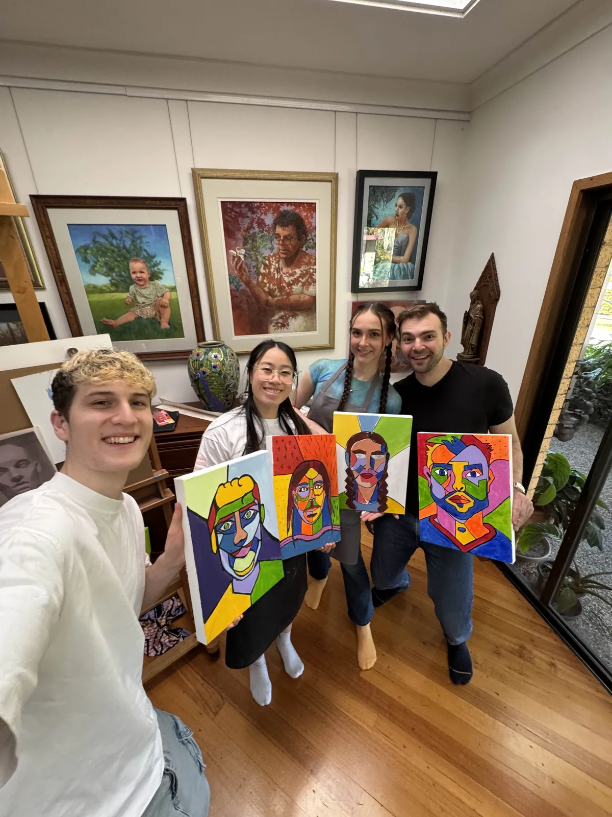 Seb and friends holding colourful portrait paintings.