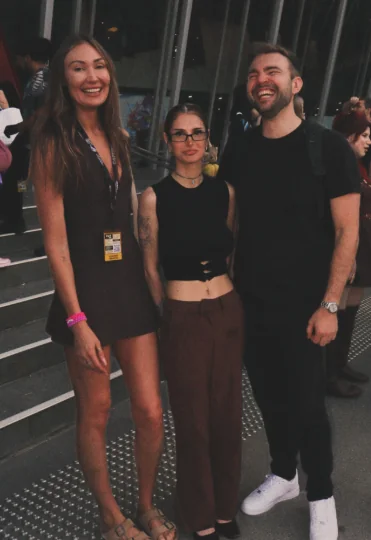 Three attendees posing together outside an event venue.