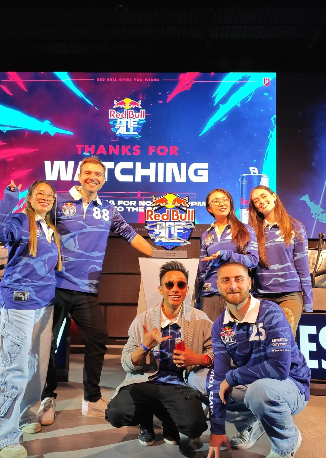 Seb and a team posing in front of a gaming event screen.