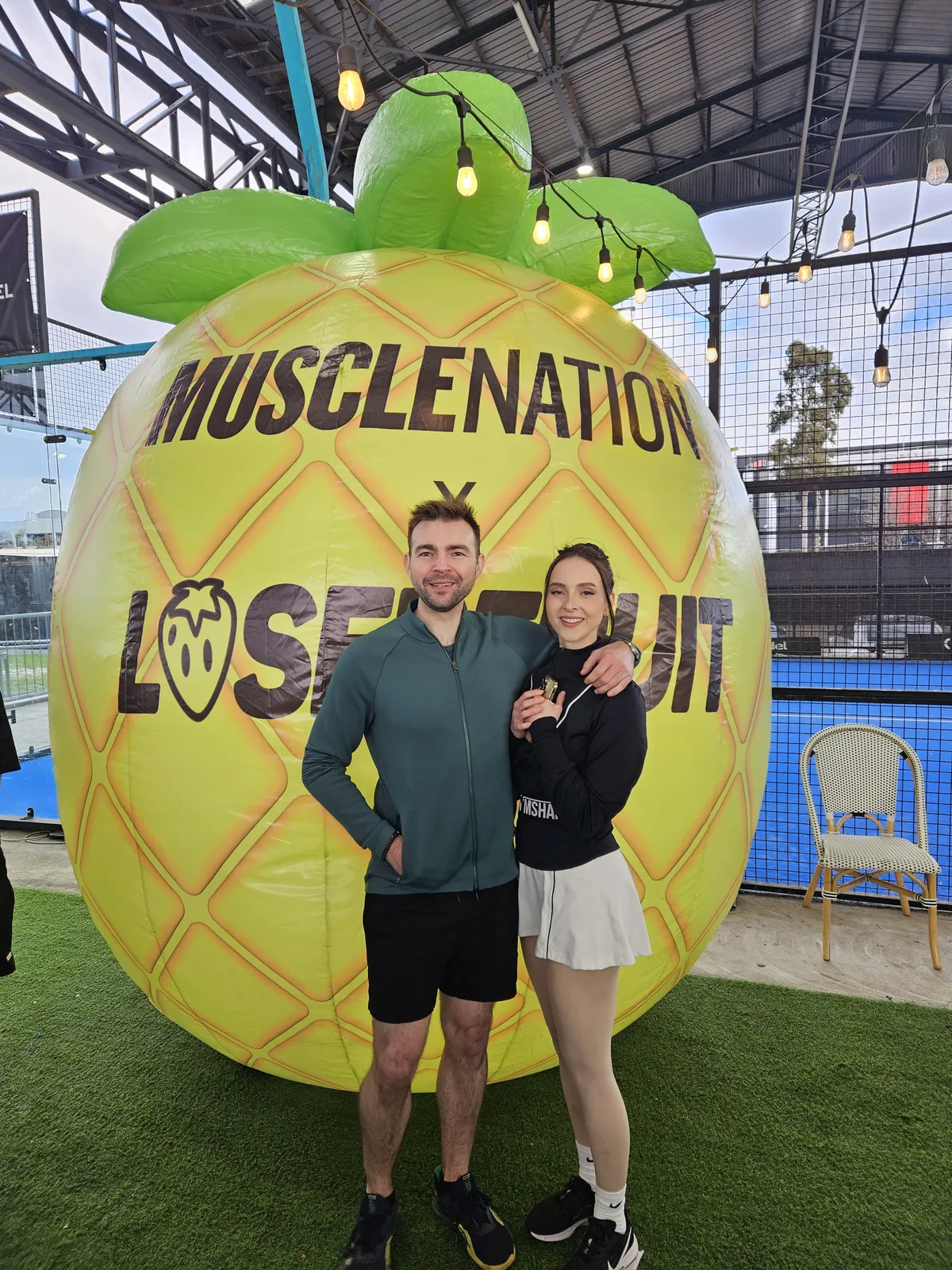 Seb and a fellow attendee standing beside a large event football installation.