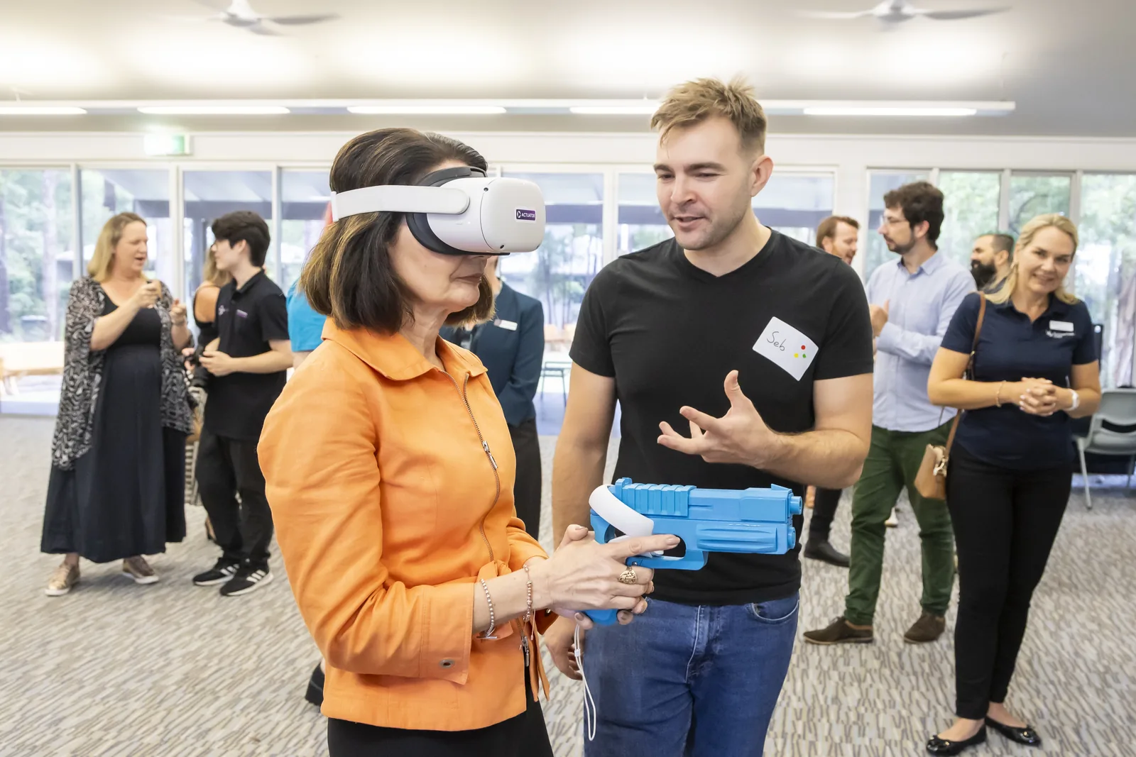 Seb guiding an attendee using a virtual reality blaster controller.